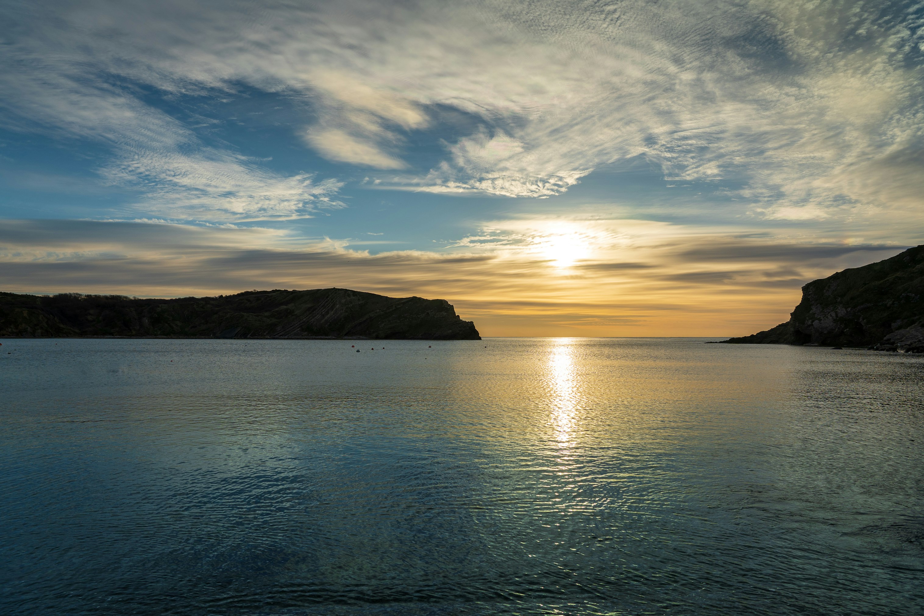 body of water near mountain during sunset